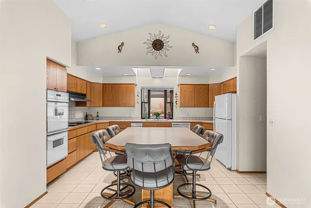 a dining room with stainless steel appliances a table and chairs