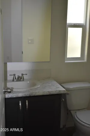 a bathroom with a granite countertop sink a toilet and a window