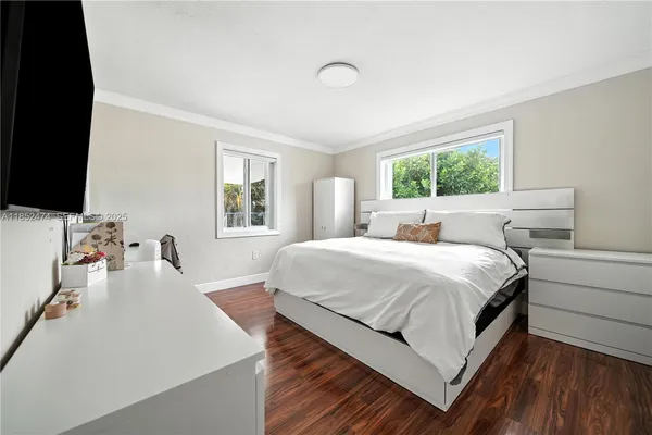 a bedroom with a bed and a flat tv screen on dresser