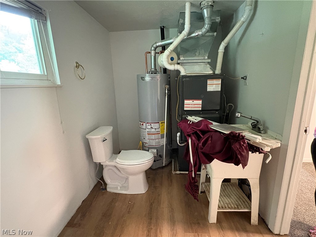 1448 Winding Road Parkersburg, WV 26104 - Photo 4 of 12 Utility area featuring wood-finish flooring, a white porcelain toilet, and a utility sink