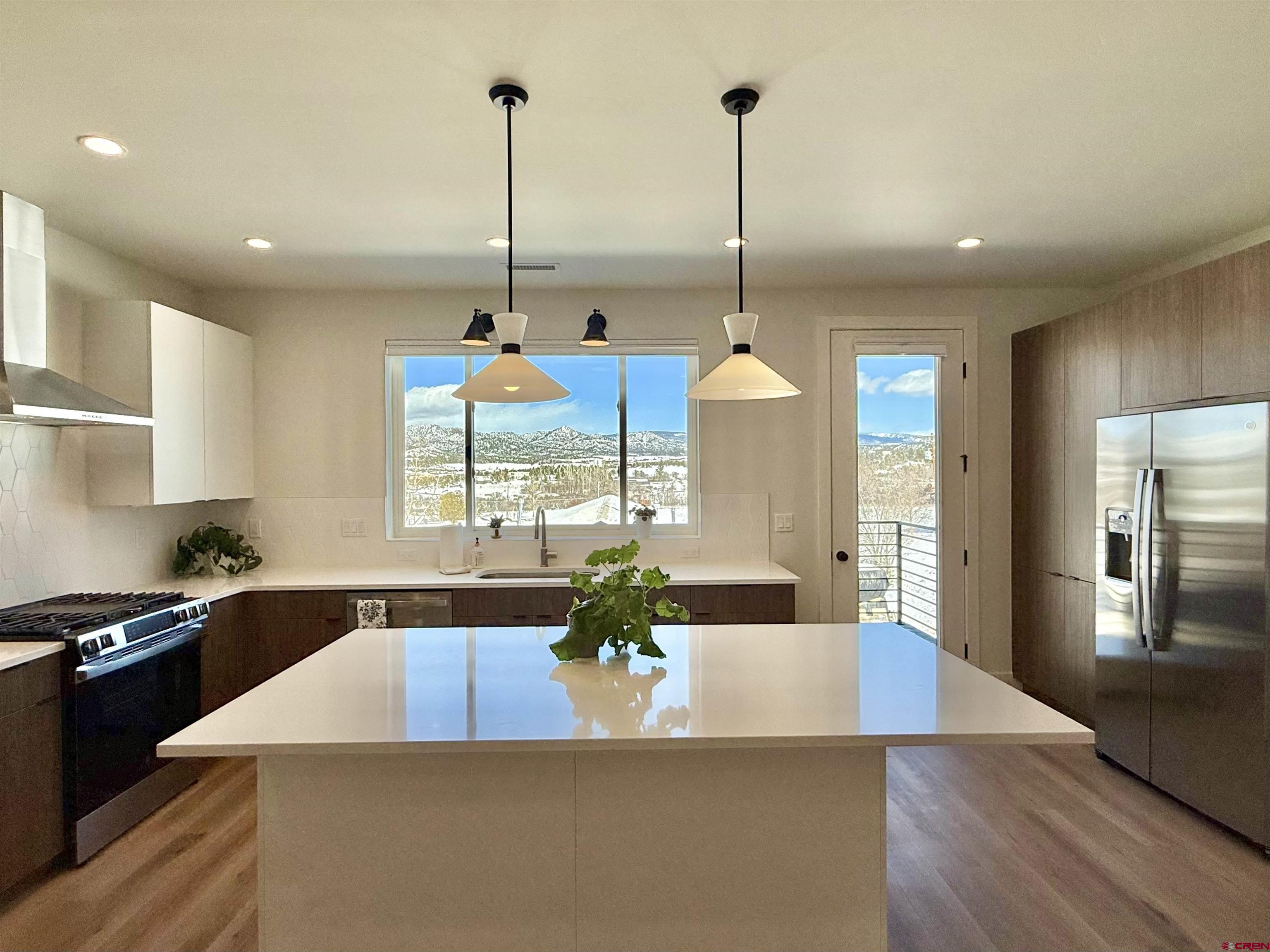 205 Treeline Street Durango, CO 81303 - Photo 13 of 39 a kitchen with stainless steel appliances kitchen island granite countertop a refrigerator a sink a dining table and chairs with wooden floor