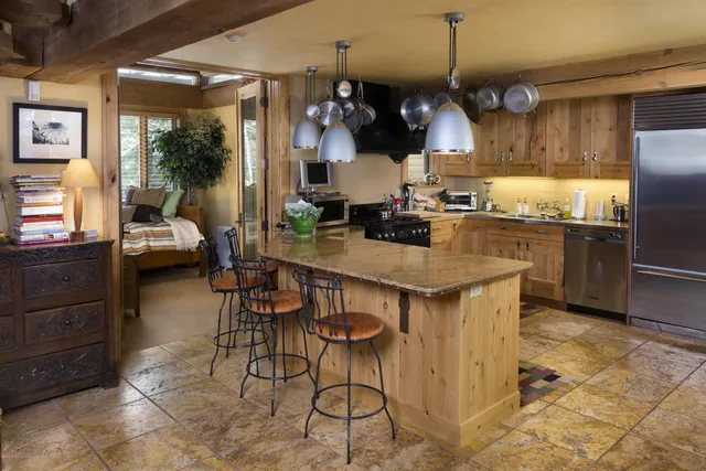 a kitchen with stainless steel appliances granite countertop a stove a refrigerator a sink a dining table and chairs with wooden floor