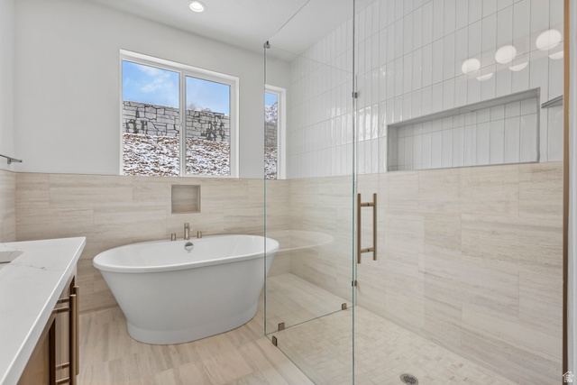 728 East Mountain Road North Ogden, UT 84414 - Photo 11 of 28 Spacious bathroom featuring a freestanding soaking tub with floor-mounted faucet, a glass-enclosed shower with subway tile surround, recessed lighting, and a white countertop vanity with dark-finish cabinetry