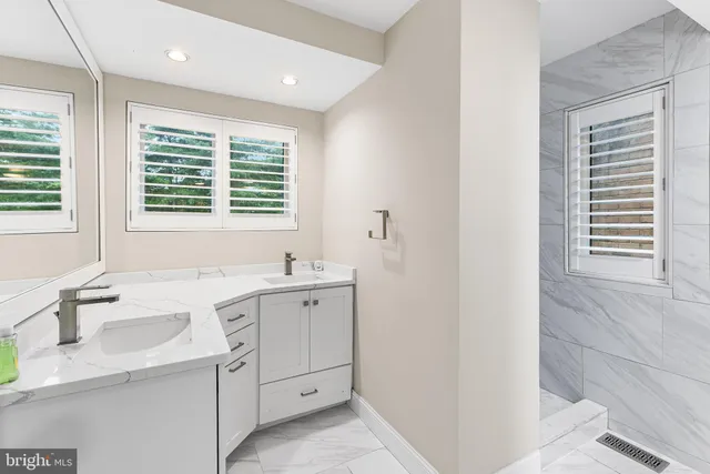 a bathroom with a granite countertop sink and a window
