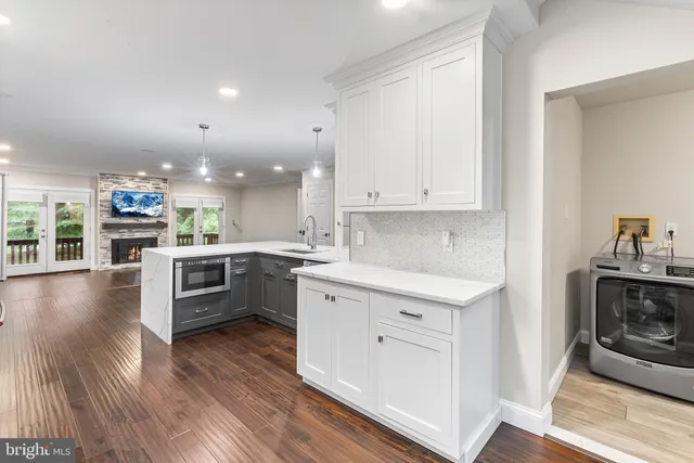 a kitchen with stainless steel appliances kitchen island granite countertop a stove a sink and white cabinets with wooden floor