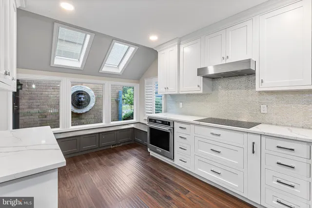 a kitchen with stainless steel appliances a stove a sink and white cabinets