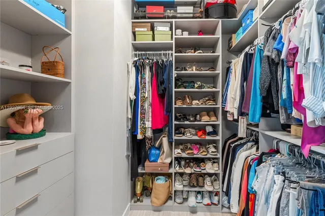 a view of walk in closet with clothes and shoes