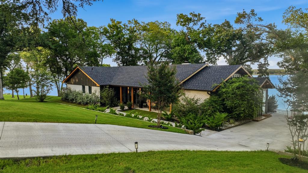 7250 Briar Road Azle, TX 76020 - Photo 6 of 40 Waterfront residence featuring a stone and wood-finish exterior, a dark shingle roof, and a concrete driveway