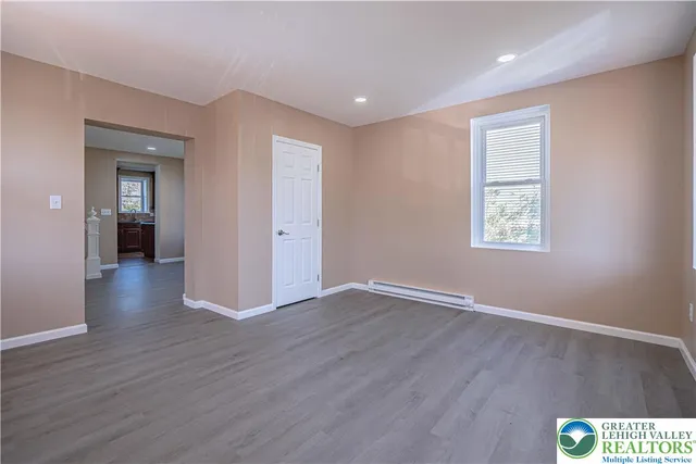 a view of an empty room with wooden floor and a window