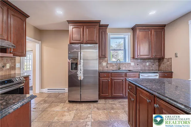 a kitchen with stainless steel appliances granite countertop a refrigerator a stove and a sink