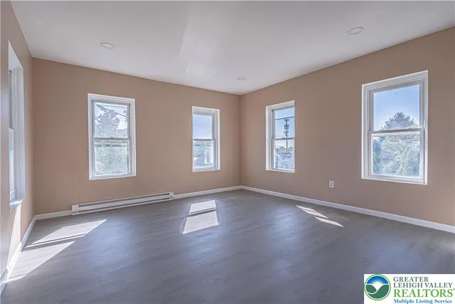 a view of an empty room with window and wooden floor
