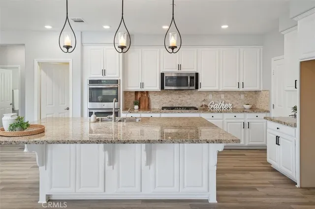a kitchen with kitchen island granite countertop a sink a counter space stainless steel appliances and cabinets