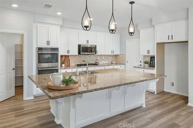 a kitchen with stainless steel appliances granite countertop a stove a sink and a microwave