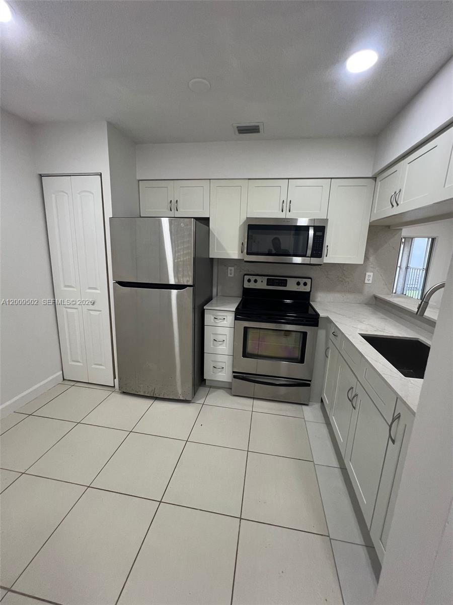 9203 Southwest 138th Place, Unit 9203 Miami, FL 33186 - Photo 11 of 22 a kitchen with cabinets and white stainless steel appliances
