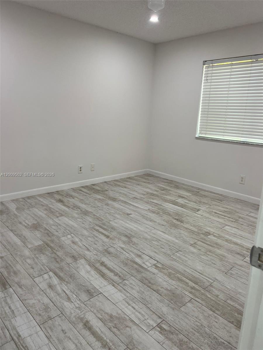 9203 Southwest 138th Place, Unit 9203 Miami, FL 33186 - Photo 15 of 22 an empty room with wooden floor and windows