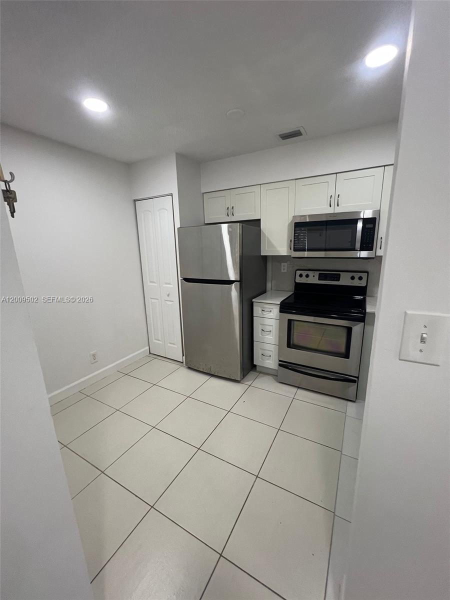 9203 Southwest 138th Place, Unit 9203 Miami, FL 33186 - Photo 5 of 22 a kitchen with a refrigerator and a stove top oven