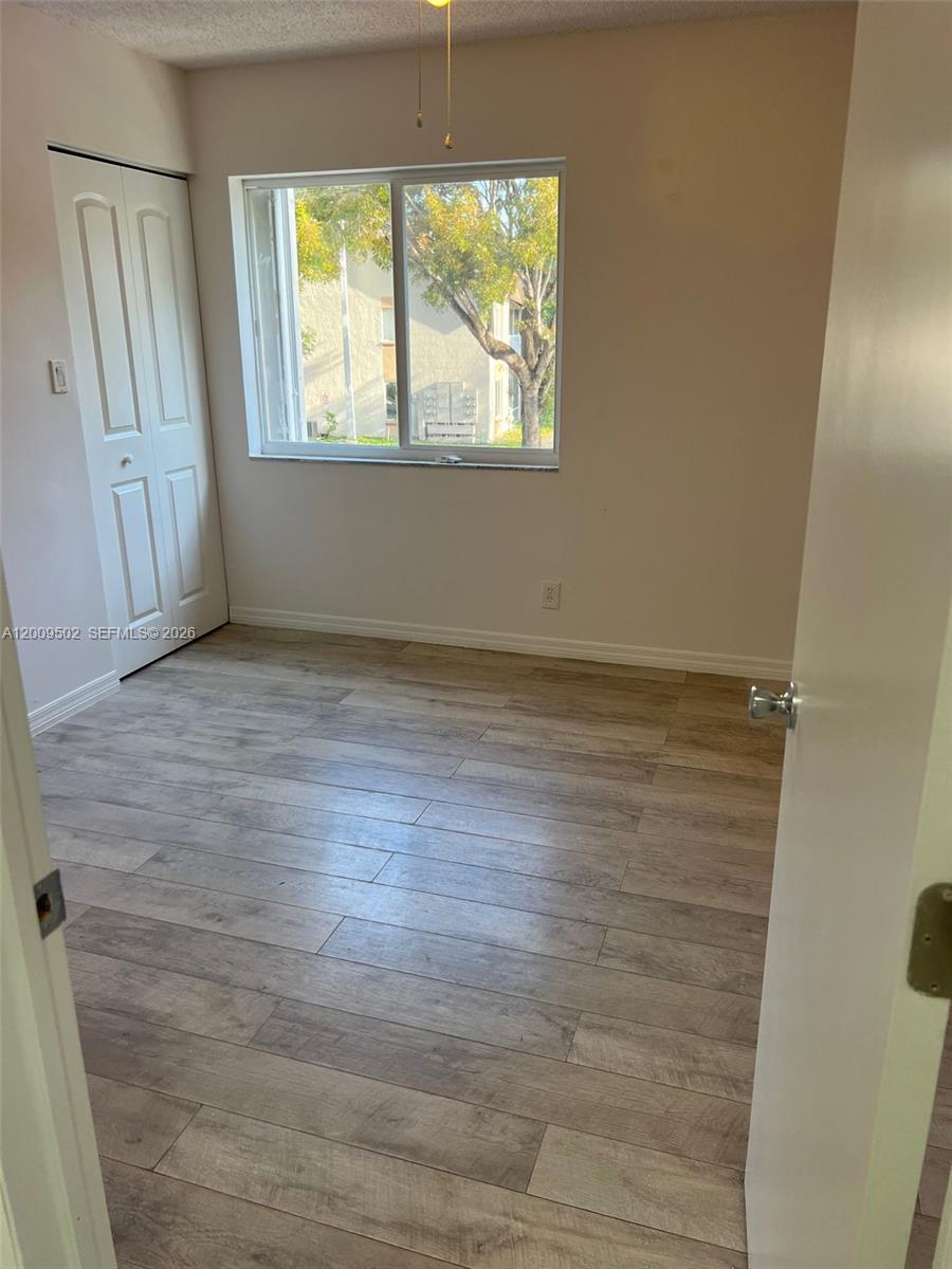 9203 Southwest 138th Place, Unit 9203 Miami, FL 33186 - Photo 6 of 22 an empty room with wooden floor and windows