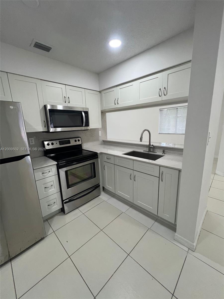 9203 Southwest 138th Place, Unit 9203 Miami, FL 33186 - Photo 10 of 22 a kitchen with kitchen island a sink appliances and cabinets