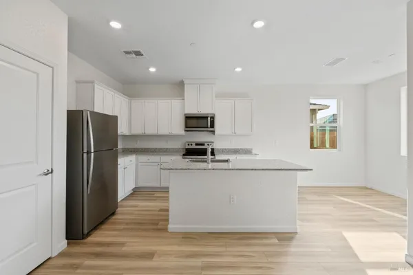 a kitchen with stainless steel appliances granite countertop a refrigerator and a stove top oven