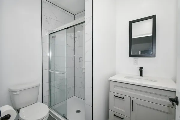 a bathroom with a shower a sink a toilet and mirror