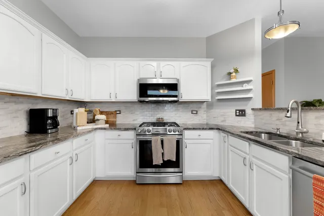 a kitchen with stainless steel appliances granite countertop a stove a sink and a microwave