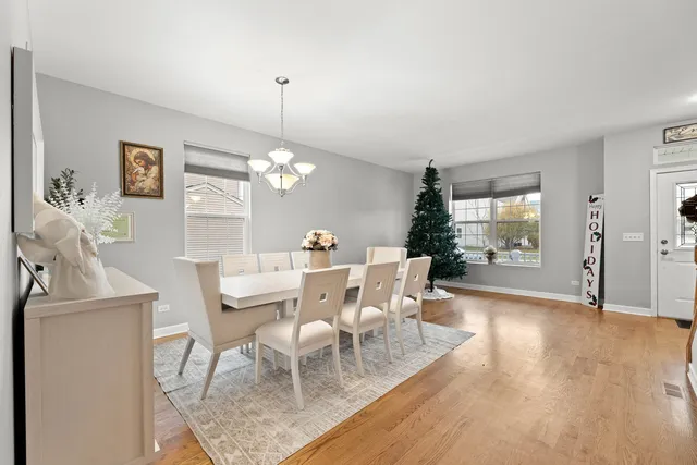 a dining room with wooden floor a chandelier a wooden table and chairs