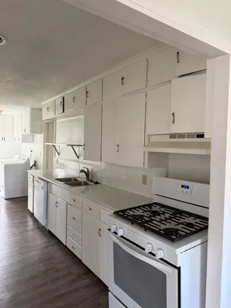 a kitchen with granite countertop white cabinets and white appliances