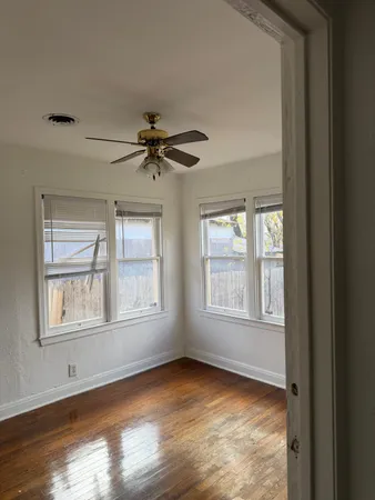 a view of an empty room with a window and wooden floor