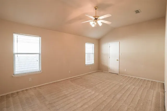 an empty room with windows and fan