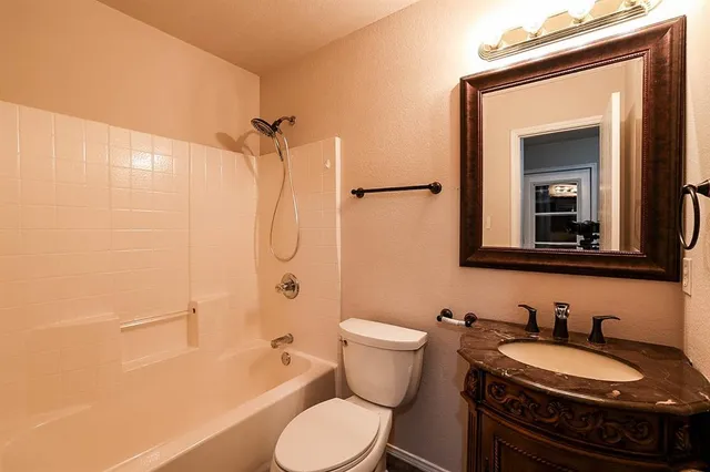 a bathroom with a granite countertop toilet sink and mirror