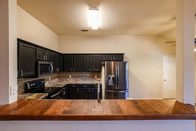 a kitchen with kitchen island granite countertop a stove and a refrigerator