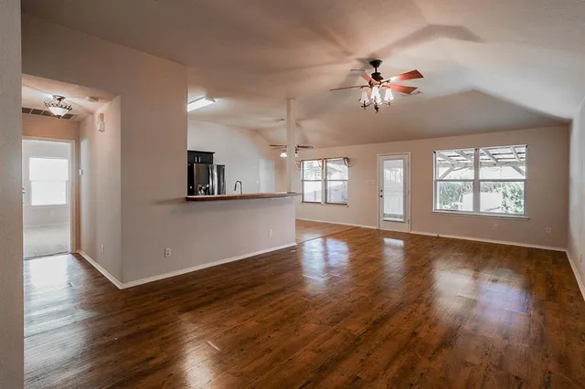 an empty room with wooden floor and windows