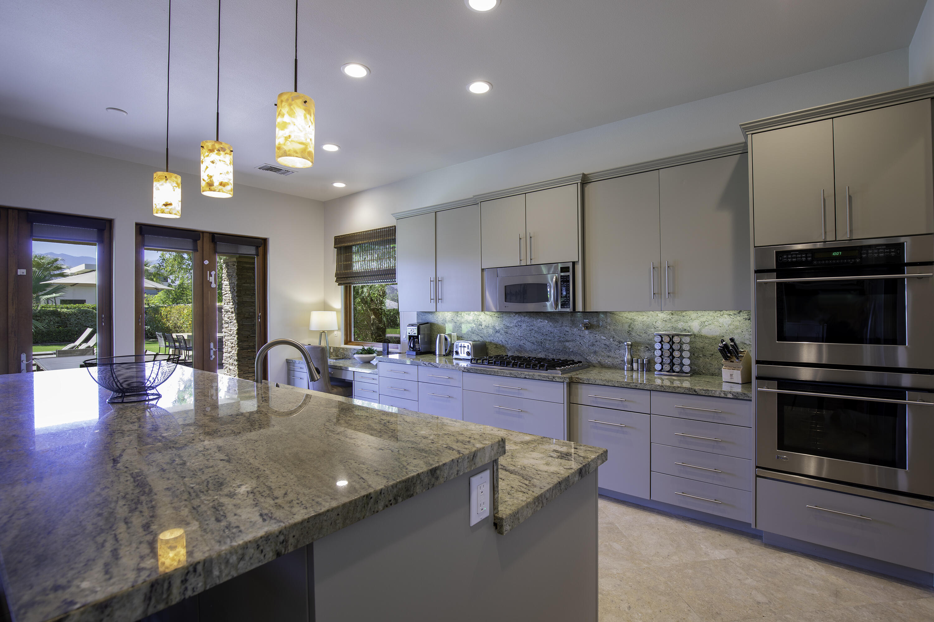 72737 Verbenia Road Rancho Mirage, CA 92270 - Photo 7 of 29 a kitchen with stainless steel appliances granite countertop a stove top oven a sink dishwasher a dining table and chairs with wooden floor