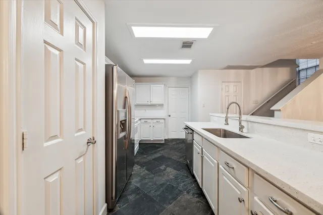 a large white kitchen with wooden floor and white appliances