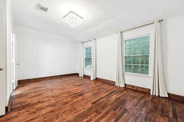 a view of an empty room with wooden floor fireplace and a window