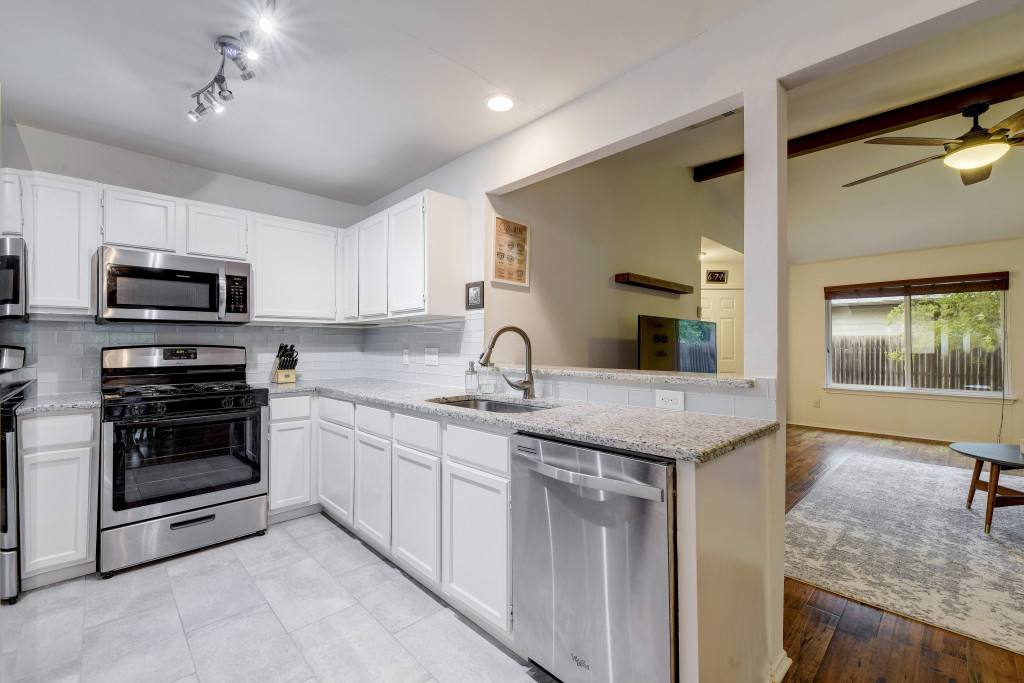 6002 Baton Rouge Drive Austin, TX 78727 - Photo 10 of 20 Kitchen featuring white cabinetry, stainless steel appliances, speckled countertops, and a subway tile backsplash
