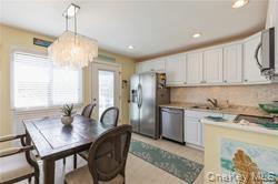 95 Springville Road, Unit 8 Hampton Bays, NY 11946 - Photo 5 of 12 a kitchen with a table chairs stove and refrigerator