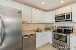 95 Springville Road, Unit 8 Hampton Bays, NY 11946 - Photo 6 of 12 a kitchen with stainless steel appliances granite countertop grey cabinets a stove a microwave and a sink