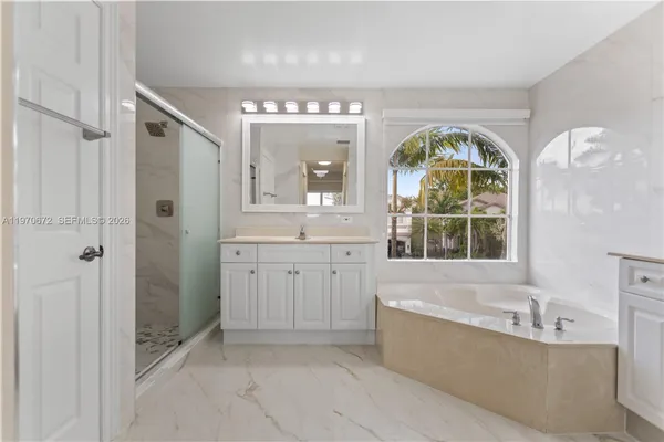 a spacious bathroom with a tub sink and mirror