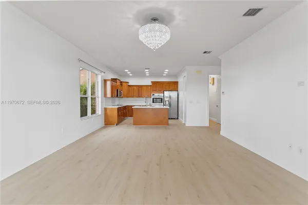 a big room with chandelier kitchen view and a window