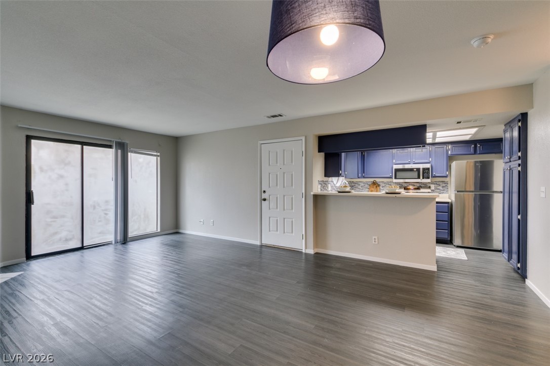 810 North Sloan Lane, Unit 103 Las Vegas, NV 89110 - Photo 12 of 16 Unfurnished living room featuring dark wood finished floors and baseboards