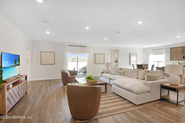 a living room with furniture a wooden floor and a flat screen tv