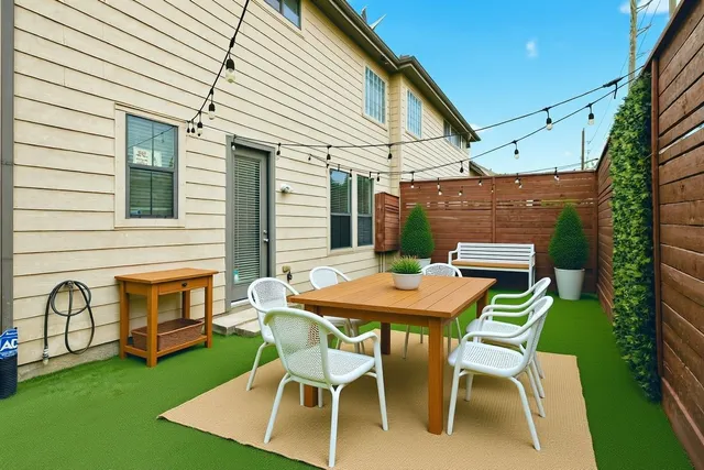 a patio with table and chairs and potted plants