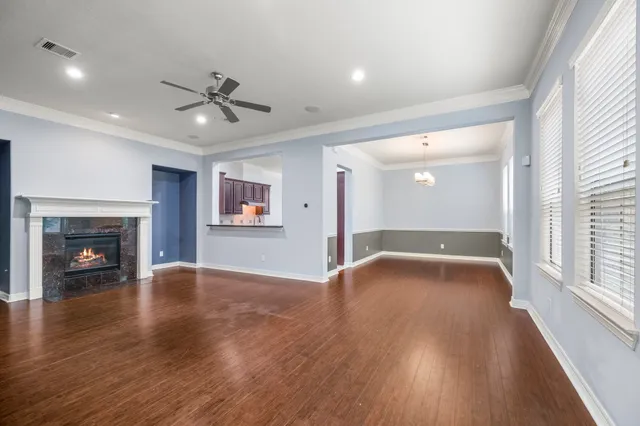 an empty room with wooden floor fireplace and windows