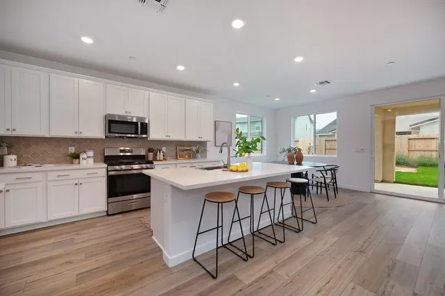 a kitchen with kitchen island a stove a table and chairs in it