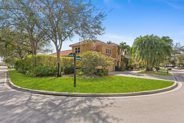 a view of a white house with a small yard and a trees