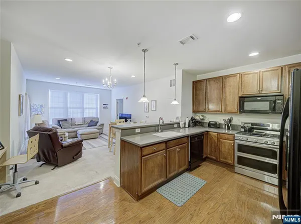 a kitchen with stainless steel appliances granite countertop a stove top oven a sink dishwasher a dining table and chairs with wooden floor