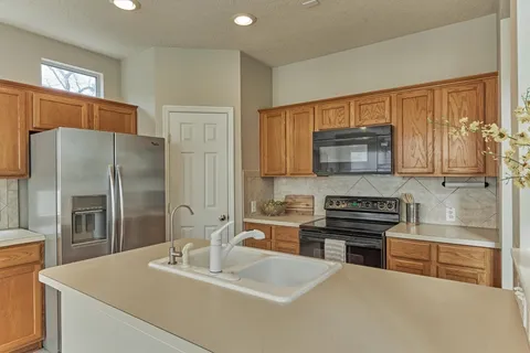 a kitchen with kitchen island a sink appliances and a counter top space