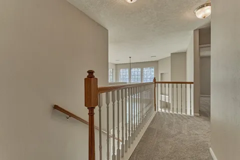a view of a brick house with large trees and wooden fence
