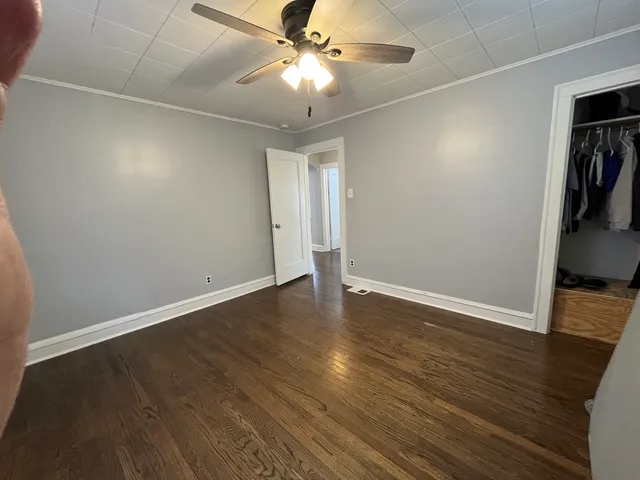 an empty room with wooden floor and ceiling fan